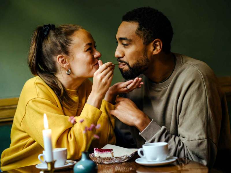 Verliebtes Paar füttert sich gegenseitig mit Kuchen.
