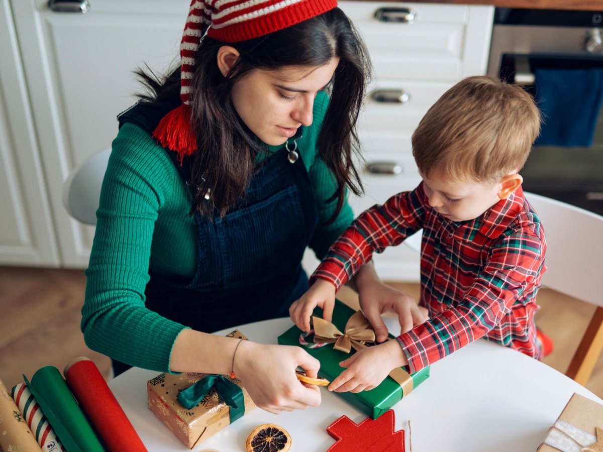 Mutter und Sohn packen zusammen Weihnachtsgeschenke ein.