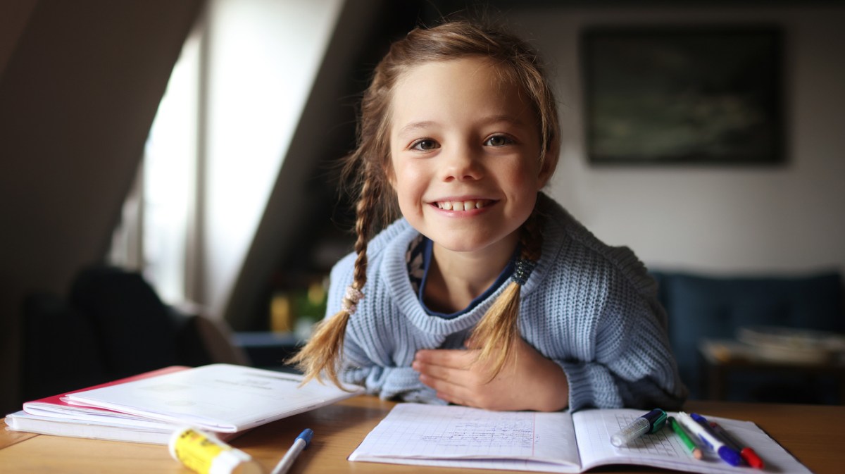 Porträt eines 8-jährigen Mädchens, das seine Hausaufgaben am Schreibtisch macht.