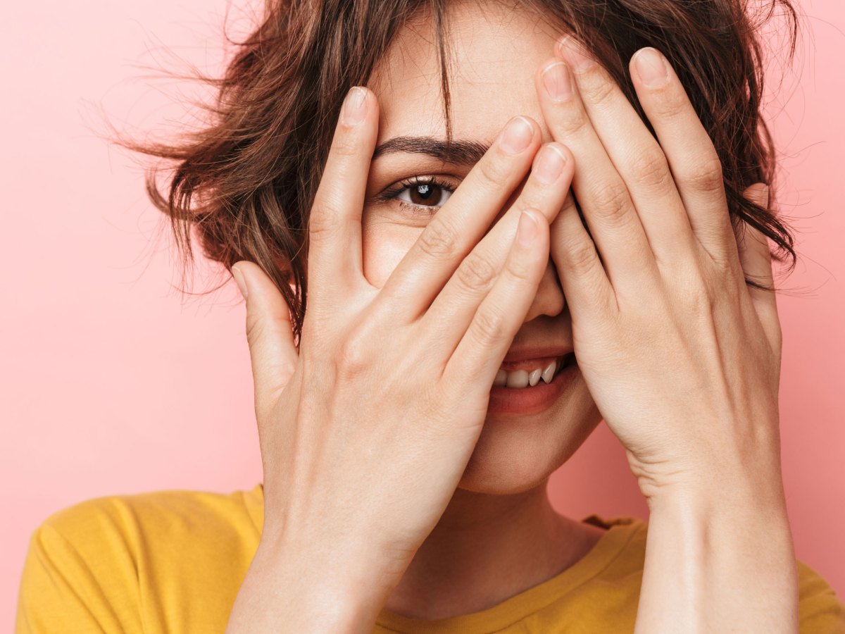 Frau hält sich lachend die Hände vor das Gesicht.
