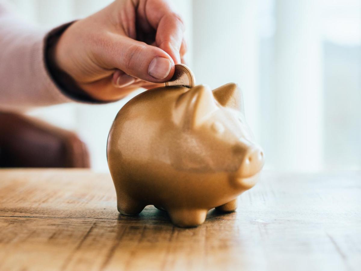 Frau wirft Geld in ein Sparschwein.