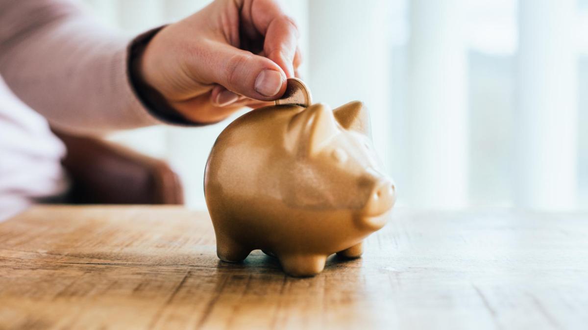 Frau wirft Geld in ein Sparschwein.