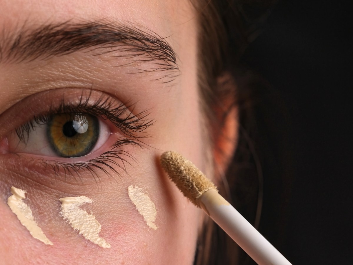 Frau trägt sich Concealer auf