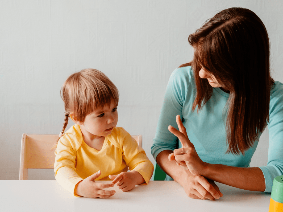 Mutter sitzt mit ihrem Kleinkind am Tisch und bringt ihm Zahlen bei