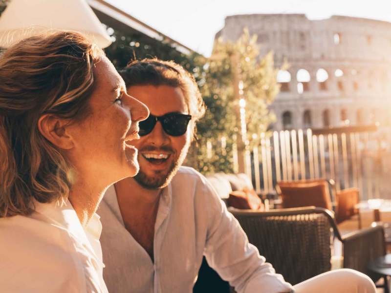 Frau und Mann sitzen draußen und lachen in der Sonne.