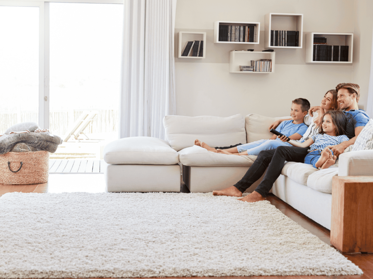 Familie sitzt im Wohnzimmer auf einer Couch
