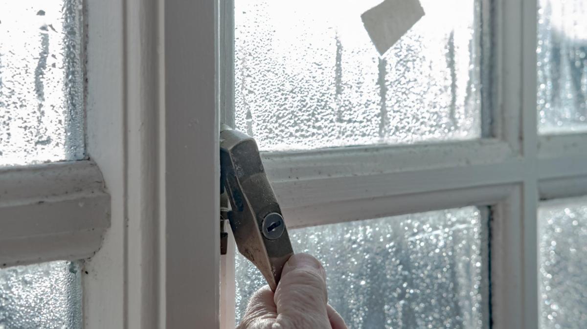 Person öffnet ein Fenster im Regen.
