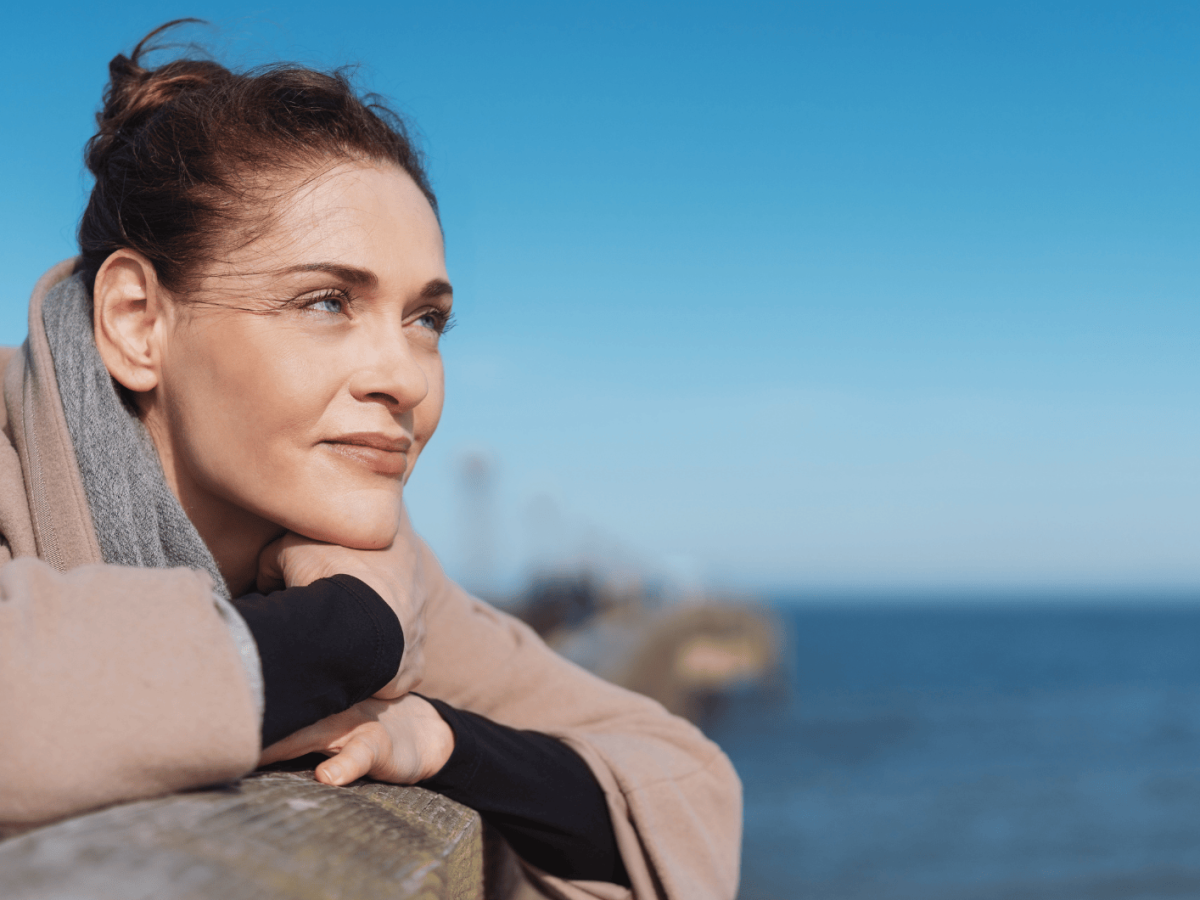 Junge Frau schaut aufs Meer hinaus.