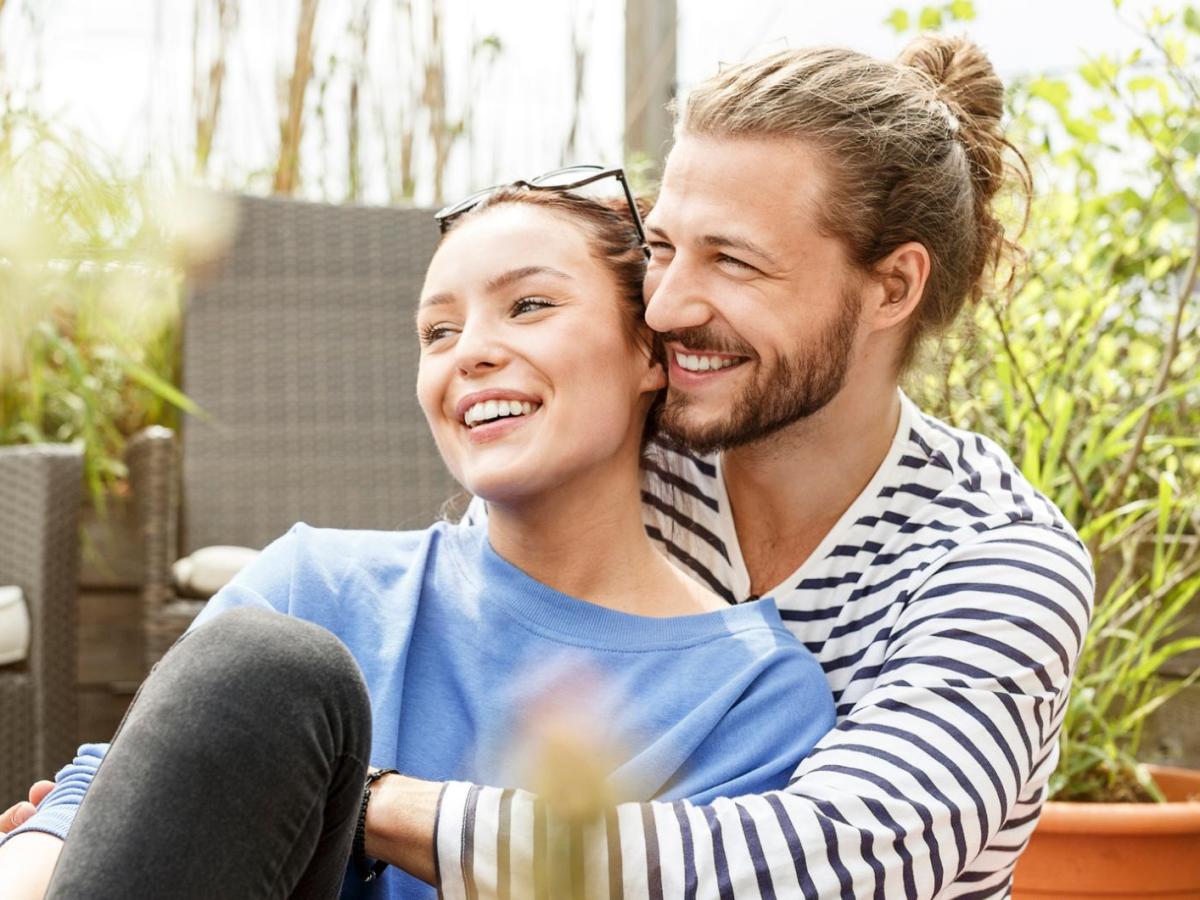 Junges Paar sitzt drau&szlig;en und kuschelt.