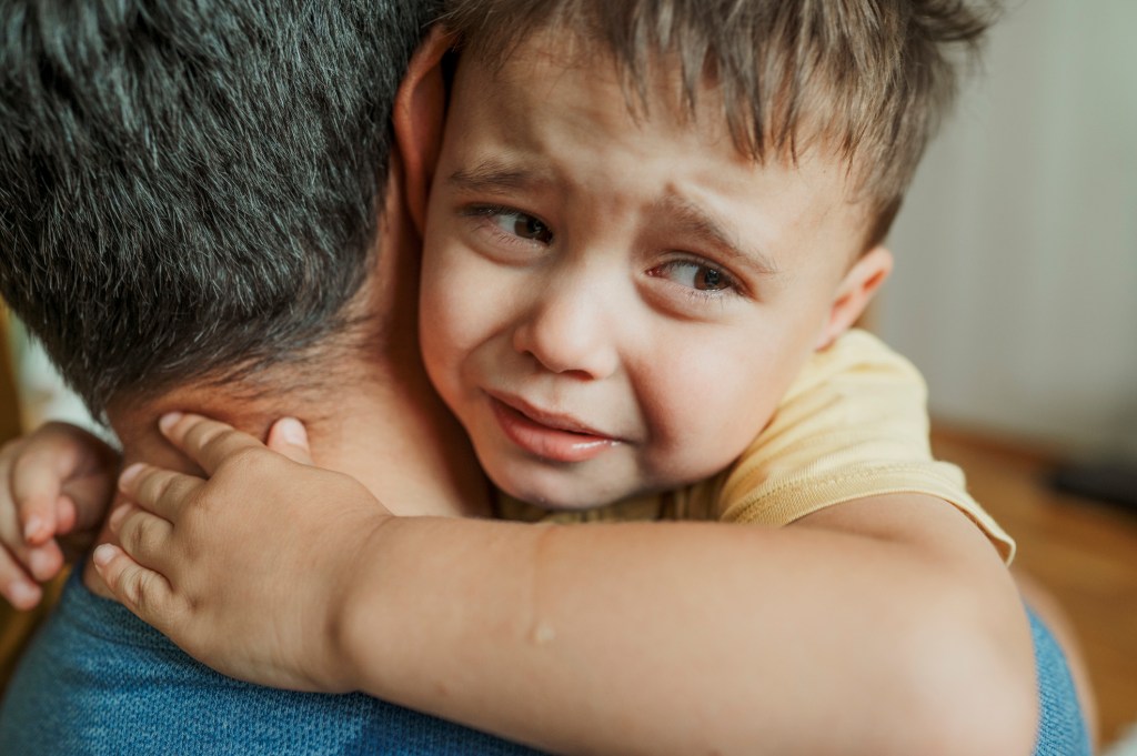 Trauriger Junge auf Arm von Papa