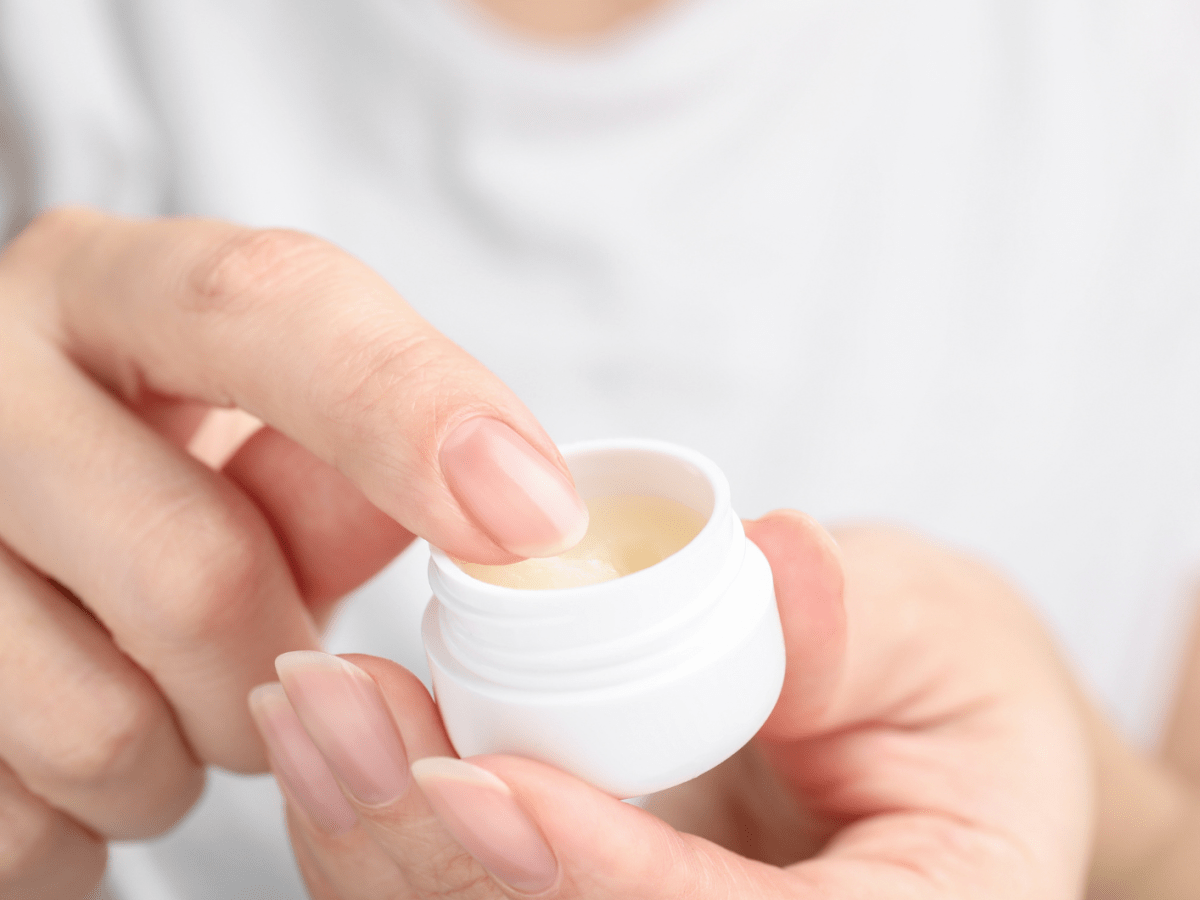 Eine Frauenhand nimmt etwas Vaseline mit dem Finger aus der Dose