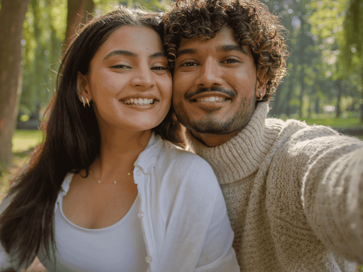 Frau und Mann lächeln für ein Selfie in die Kamera