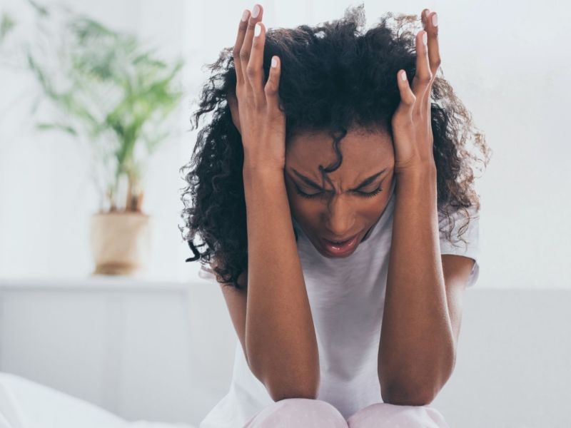 Ersch&ouml;pfte afroamerikanische Frau leidet unter Kopfschmerzen im Schlafzimmer