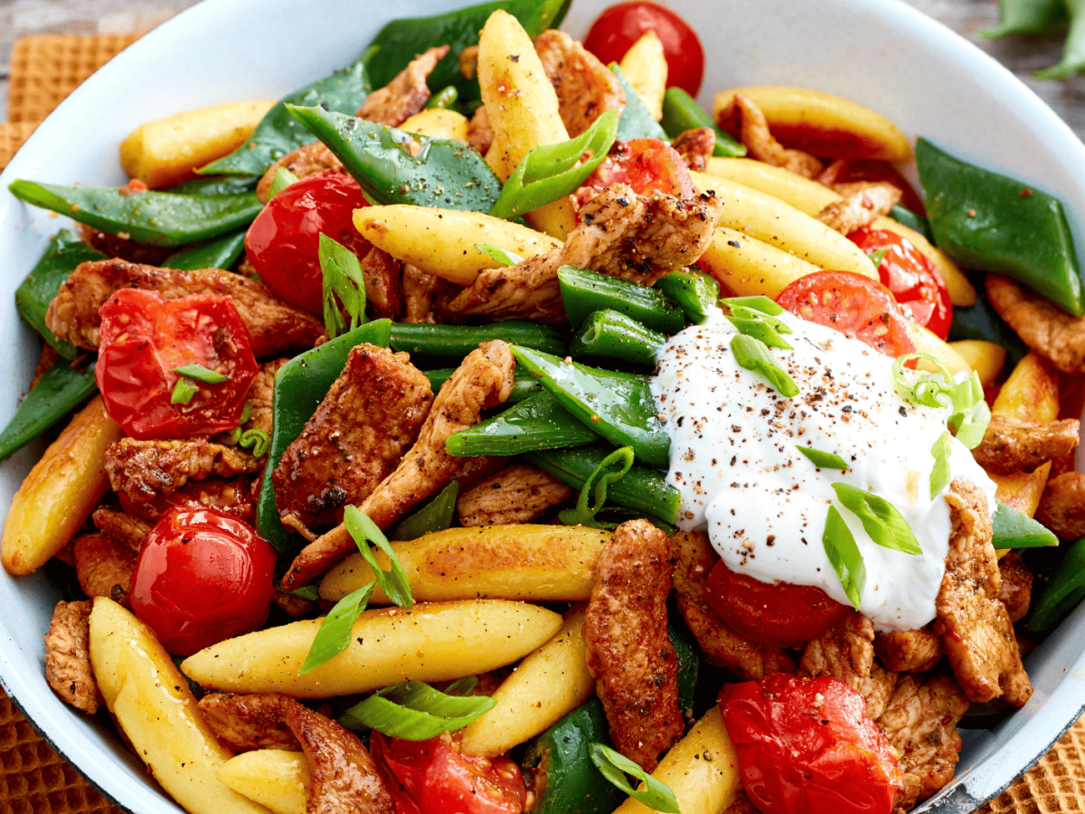 Gyros-Schupfnudel-Pfanne mit Tomaten und gr&uuml;nen Bohnen auf einem wei&szlig;en Teller.
