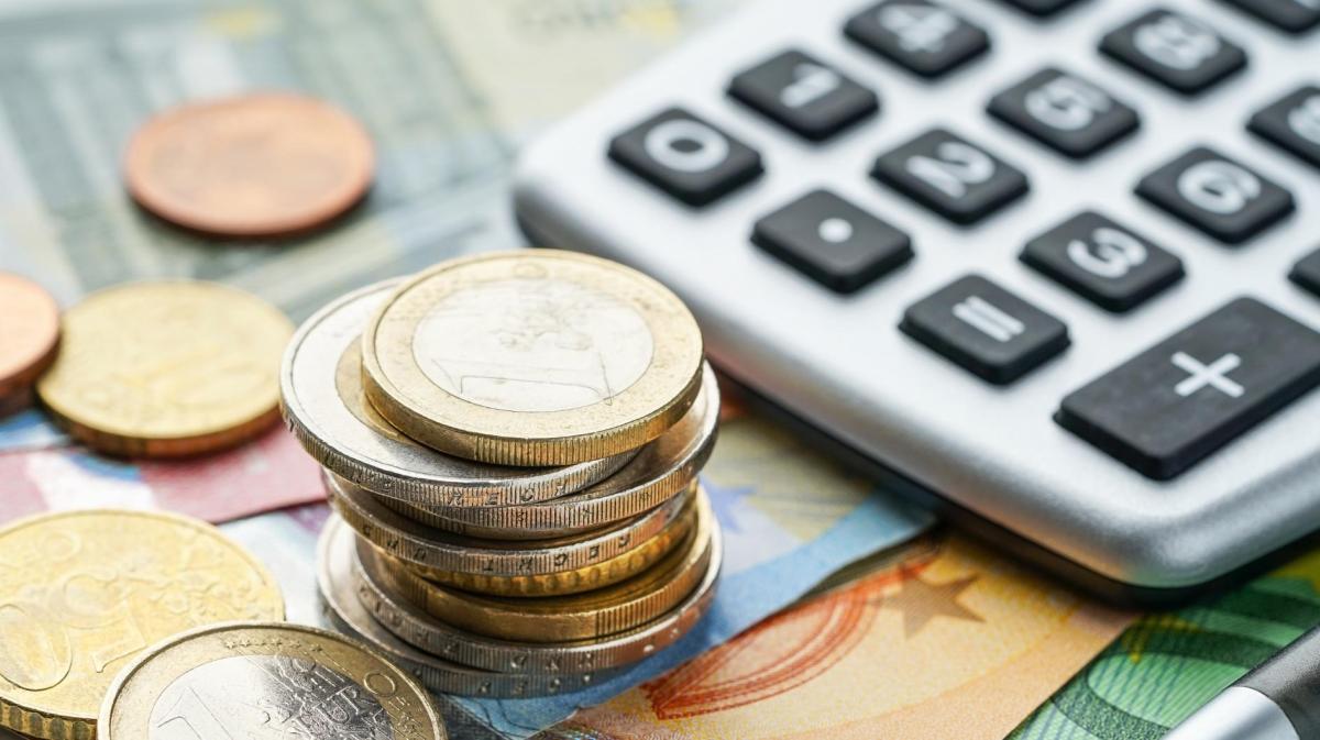 Scheine und Münzgeld liegen gestapelt neben einem Taschenrechner.