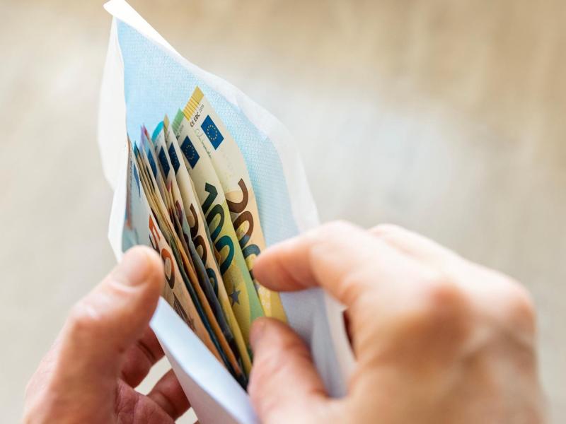 Frau legt Geld in einen Briefumschlag.