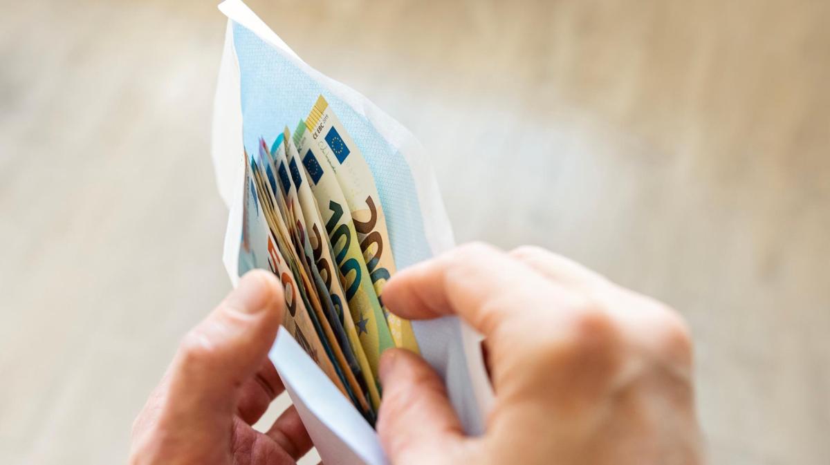 Frau legt Geld in einen Briefumschlag.