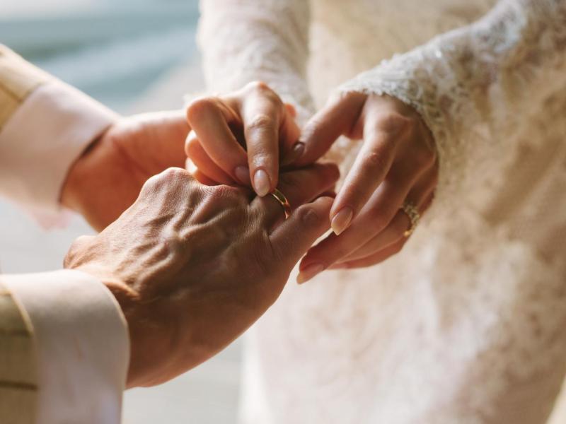 Br&auml;utigam und Braut stecken sich gegenseitig den Ring an den Finger.