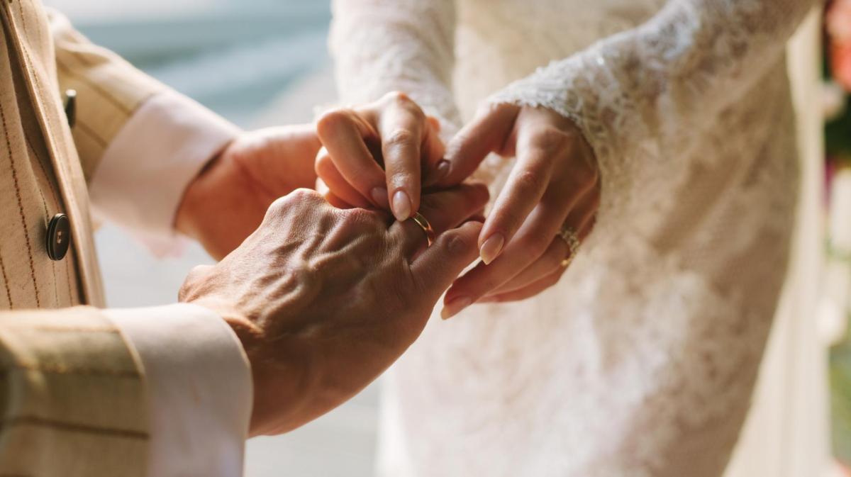 Bräutigam und Braut stecken sich gegenseitig den Ring an den Finger.