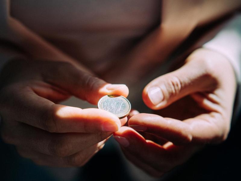 Frau hat einen Euro zwischen den Fingern.