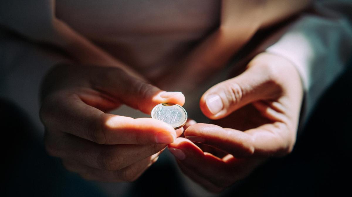 Frau hat einen Euro zwischen den Fingern.