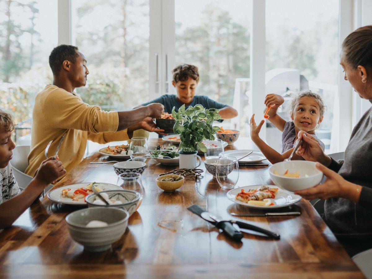5-k&ouml;pfige Familie sitzt zusammen am Tisch und isst.
