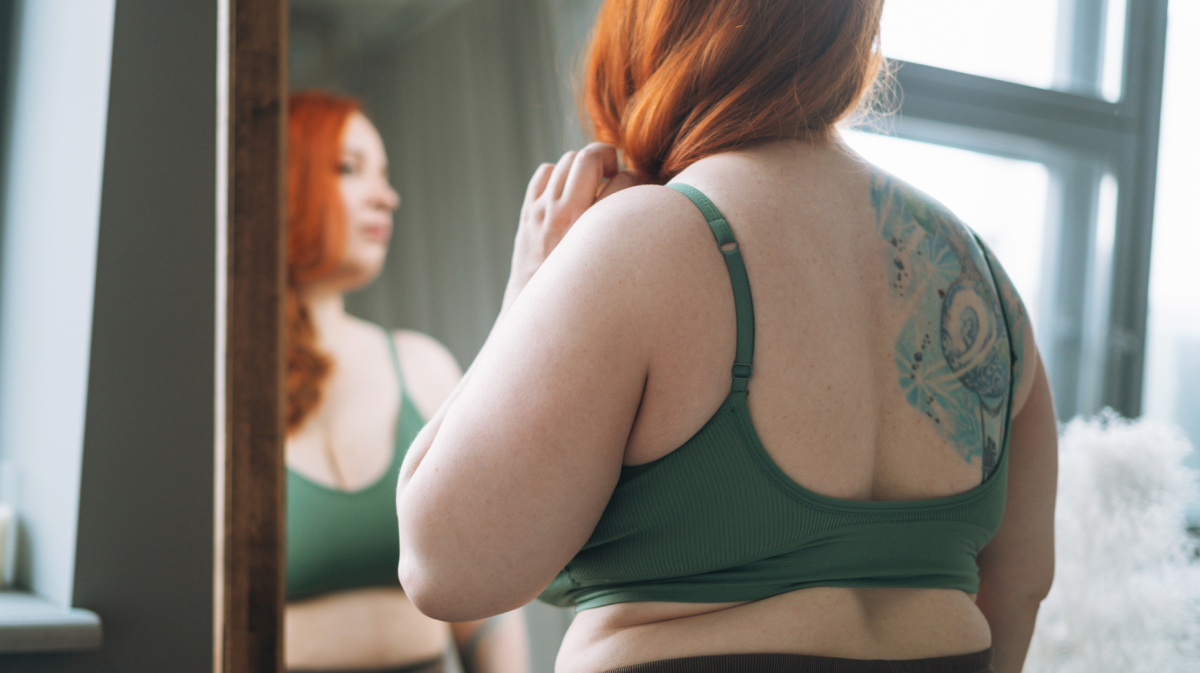 Frau mit hohem BMI steht vor dem Spiegel