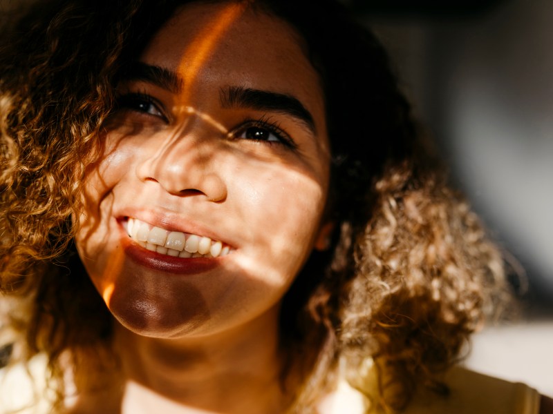 Frau lächelt und hat Sonnenreflexe im Gesicht