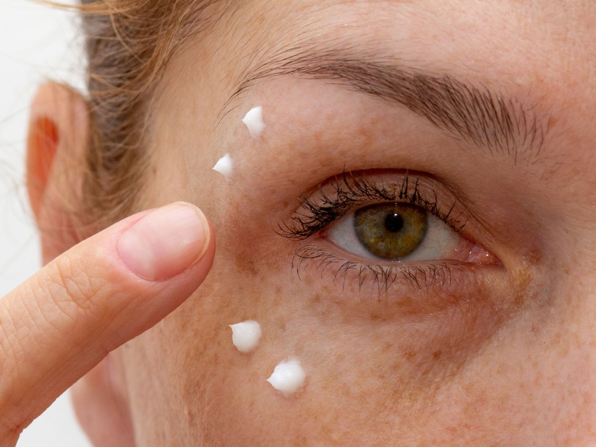 Frau, die eine Creme um die Falten ihrer Augen aufträgt.