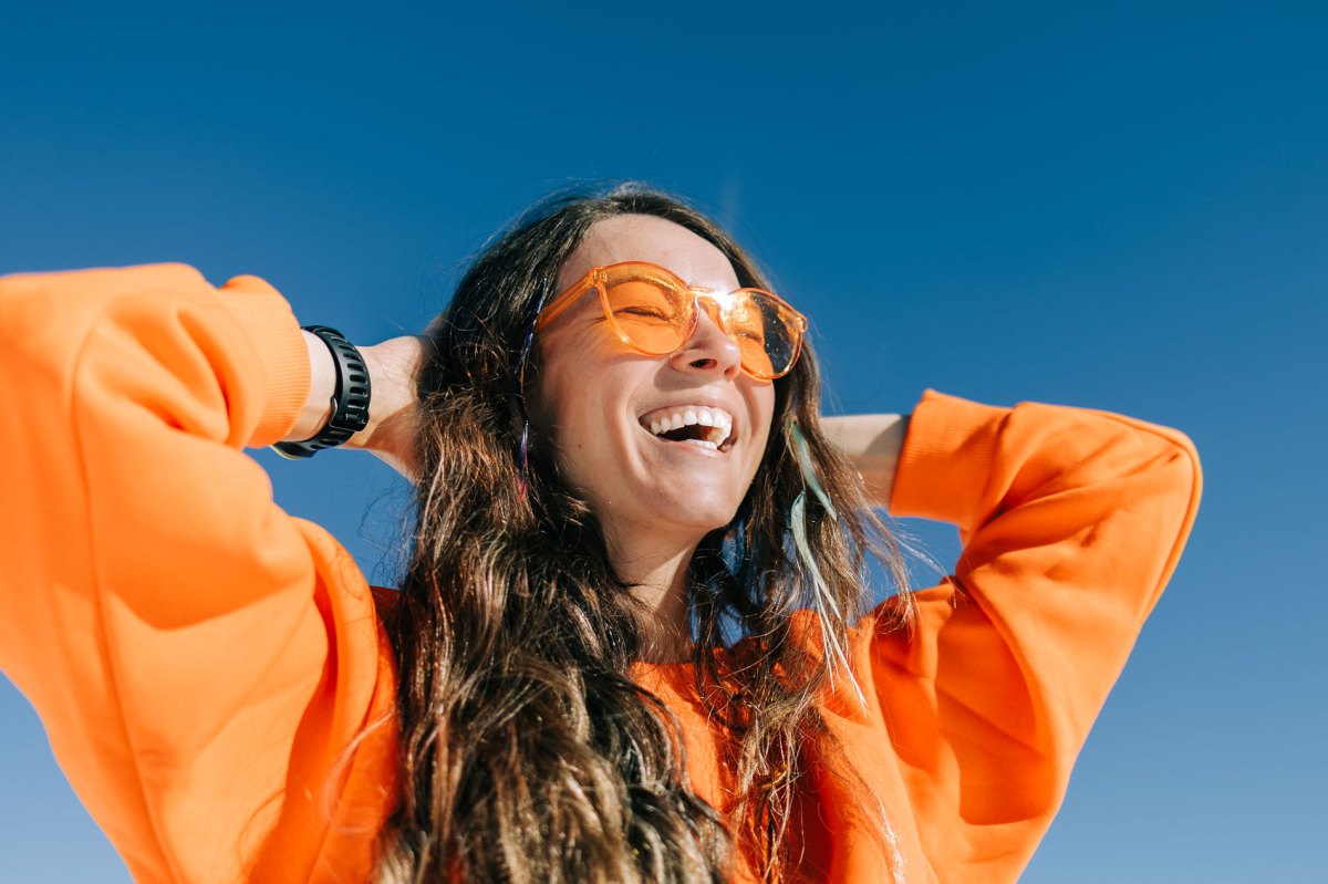 Frau in orangefarbenem Sweatshirt und Brille