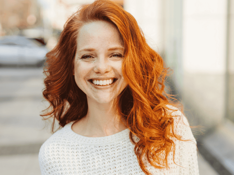Frau mit roten Locken lächelt in die Kamera