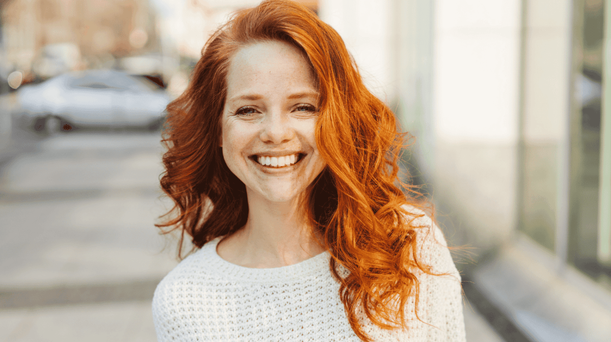 Frau mit roten Locken lächelt in die Kamera