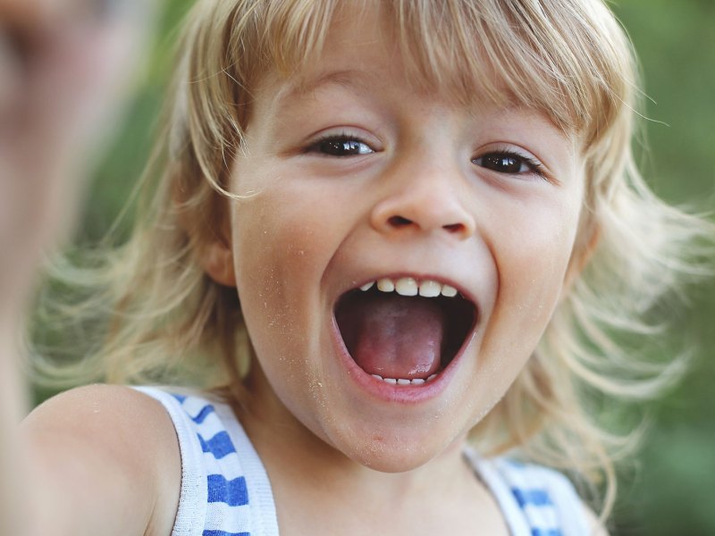 Close-up eines kleinen Jungen, der in die Kamera lacht.