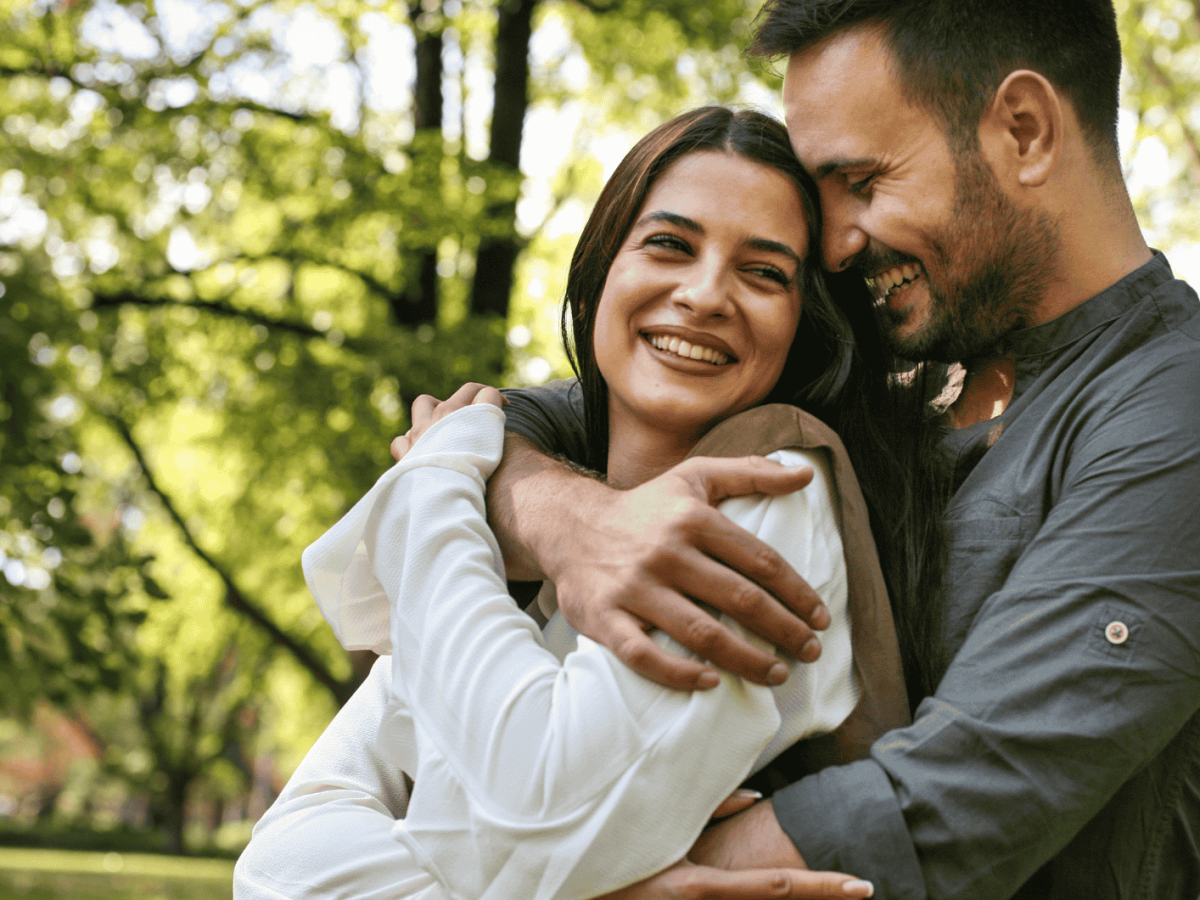 Mann umarmt Frau von hinten im Wald