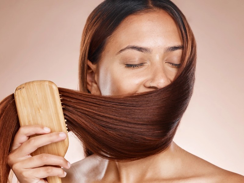 Frau, die ihre langen Haare vor die Nase hält und daran riecht.