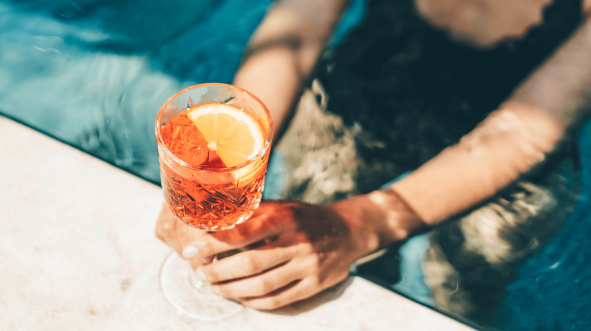 Schöne Frau trinkt Sommercocktail am Schwimmbad.
