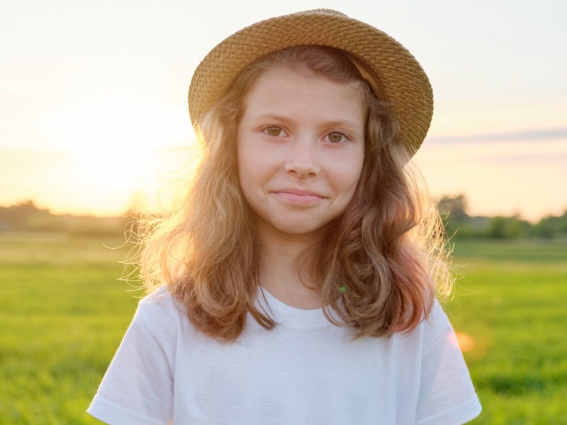 Mädchen, ca. 10 Jahre alt, an einem Sommerabend auf einer weitläufigen Wiese.