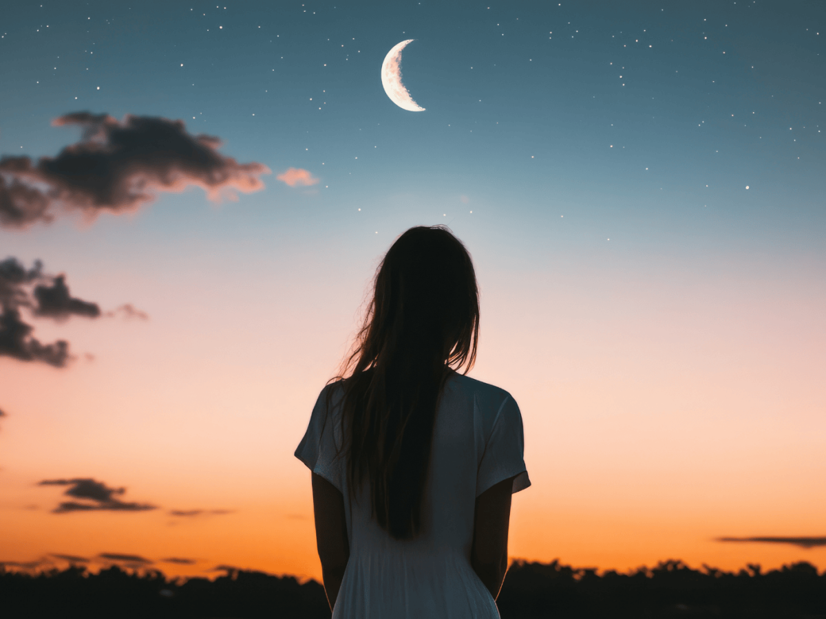 R&ouml;tlicher Himmel mit Mondsichel, eine Frau schaut hinauf.