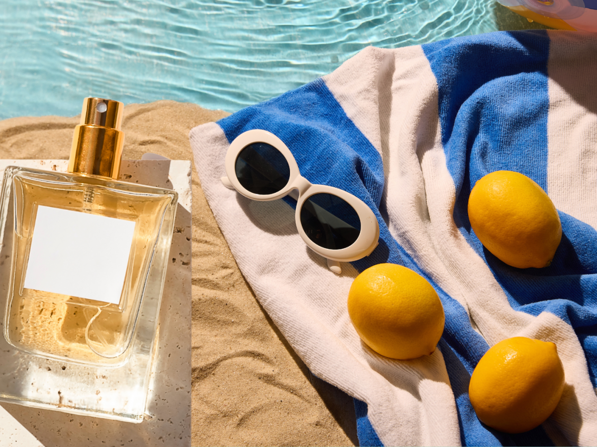 Parfum auf Sand mit Handtuch und Sonnenbrille
