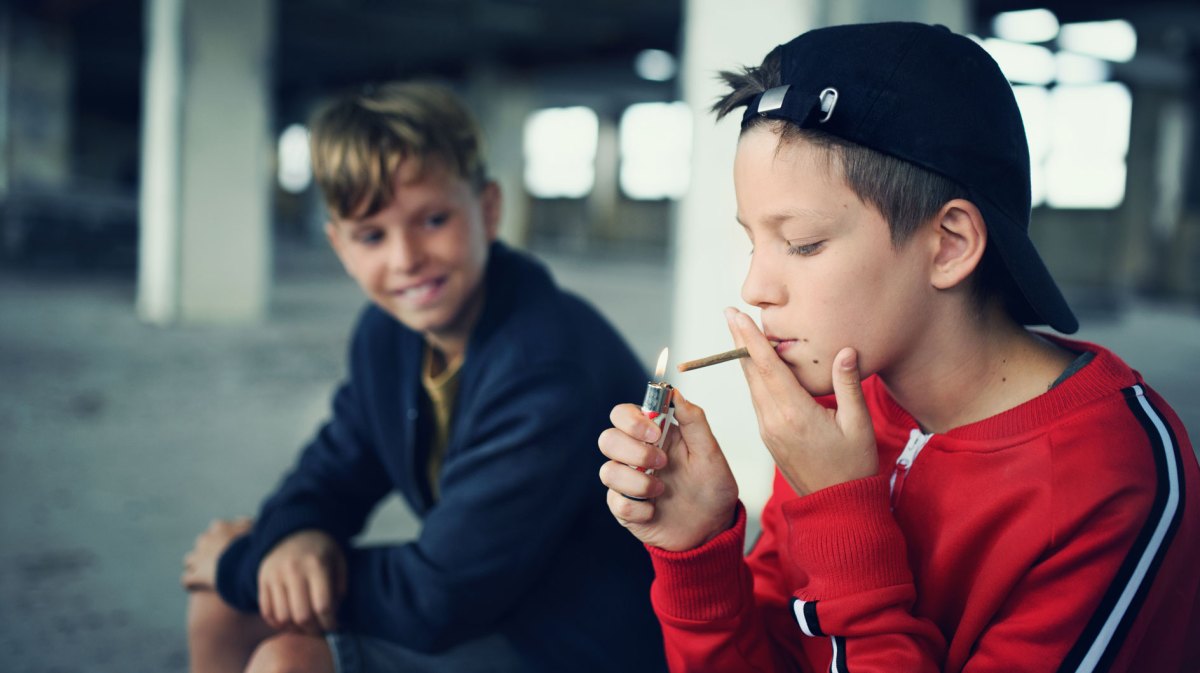 Jungs im Teenageralter, in einer Garage, rauchen heimlich.
