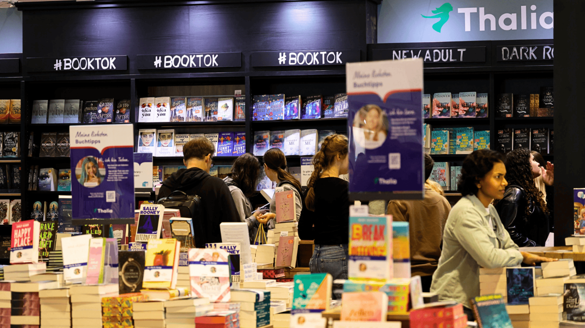 In einem Thalia-Shop, Bücher sind zu sehen und Menschen, die darin stöbern.