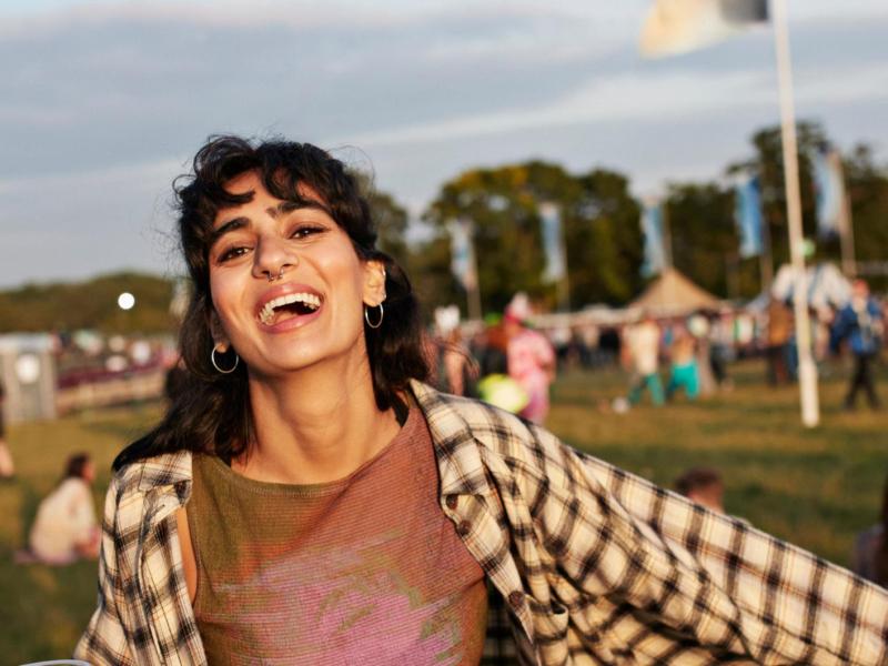 Junge Frau mit schwarzen kurzen Haaren hat Spaß auf einem Festival.