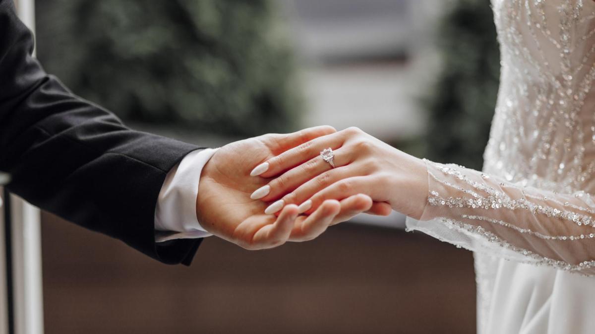 Bräutigam hält die Hand seiner Braut sanft.