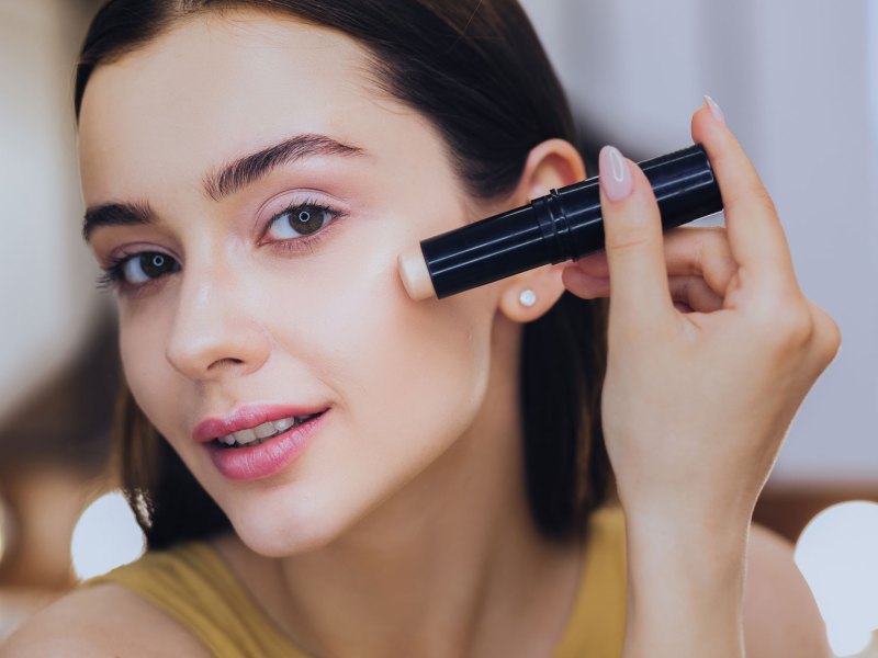 Frau, die mit einem Stift Make-up aufträgt.