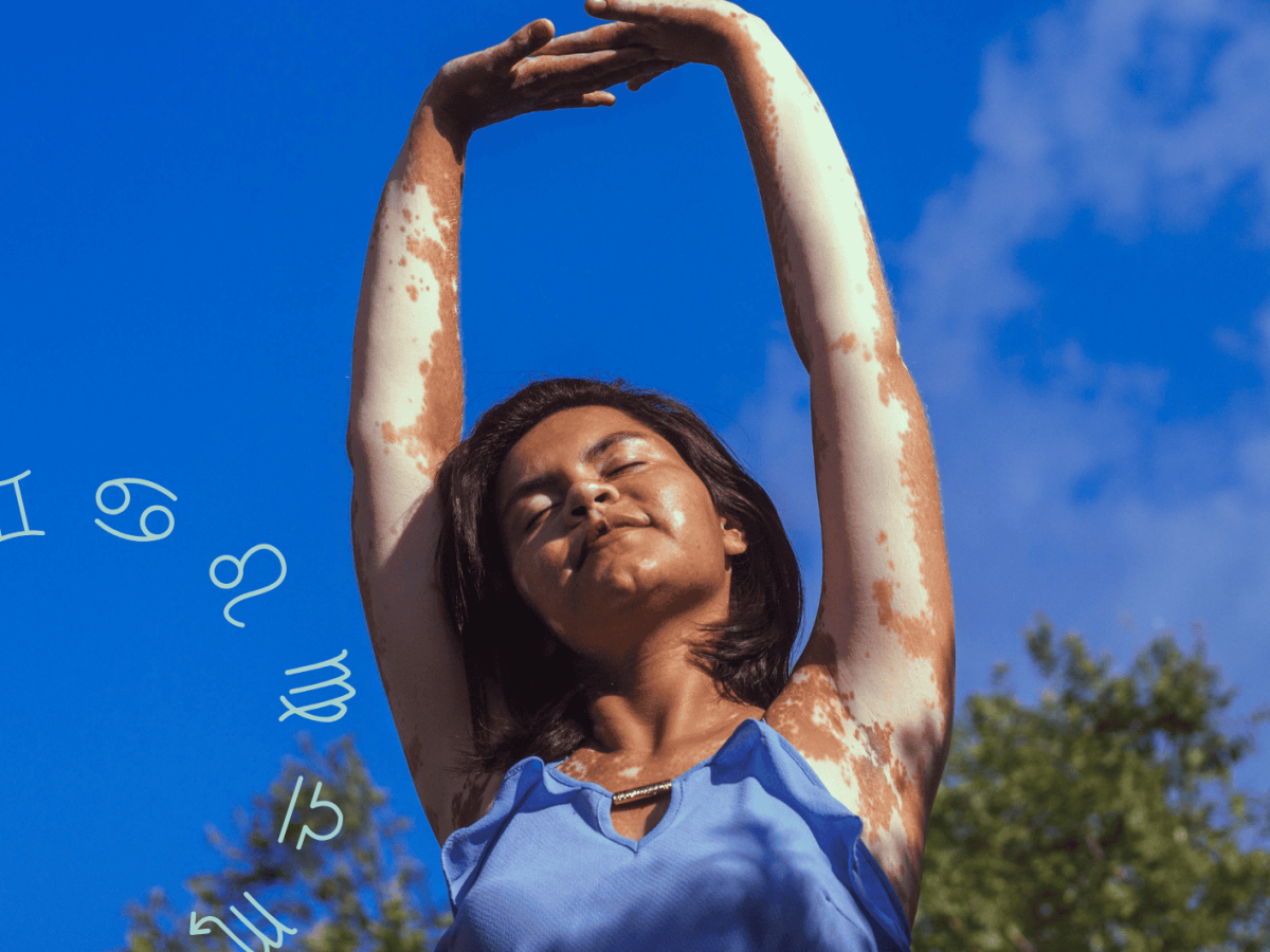 Frau mit blauem Oberteil streckt Arme in die Luft vor blauem Himmel
