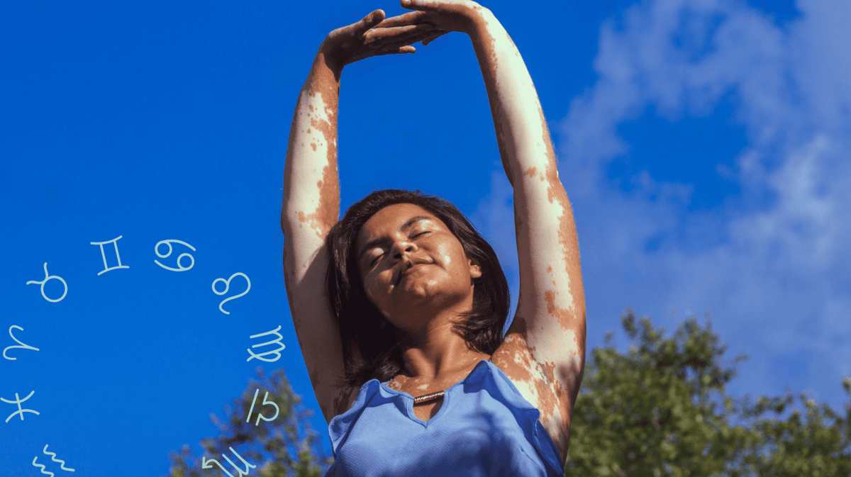 Frau mit blauem Oberteil streckt Arme in die Luft vor blauem Himmel