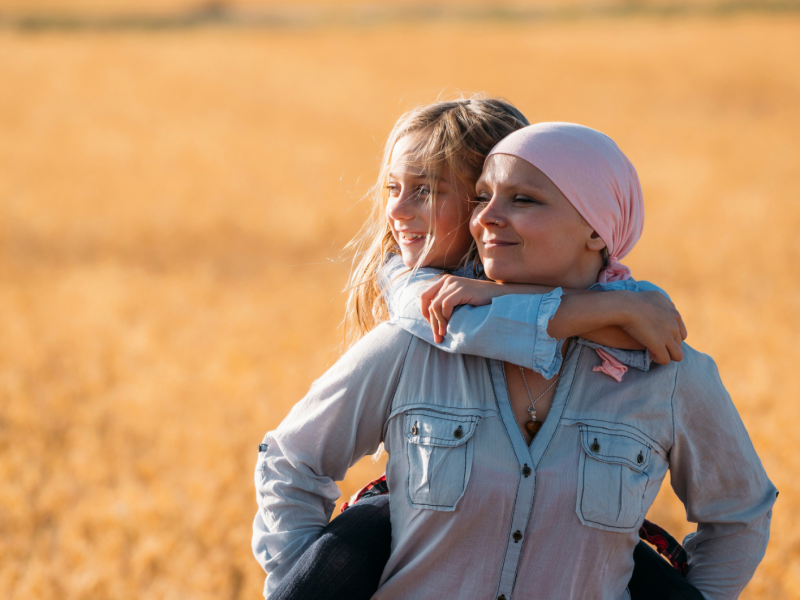 zwei Frauen stehen in einem Kornfeld, eine davon trägt ein Kopftuch