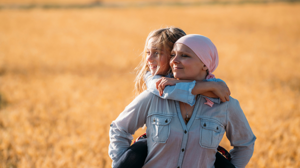 zwei Frauen stehen in einem Kornfeld, eine davon trägt ein Kopftuch