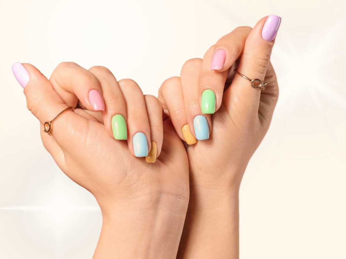 Bunt lackierte Fingernägel vor einem gelben Hintergrund