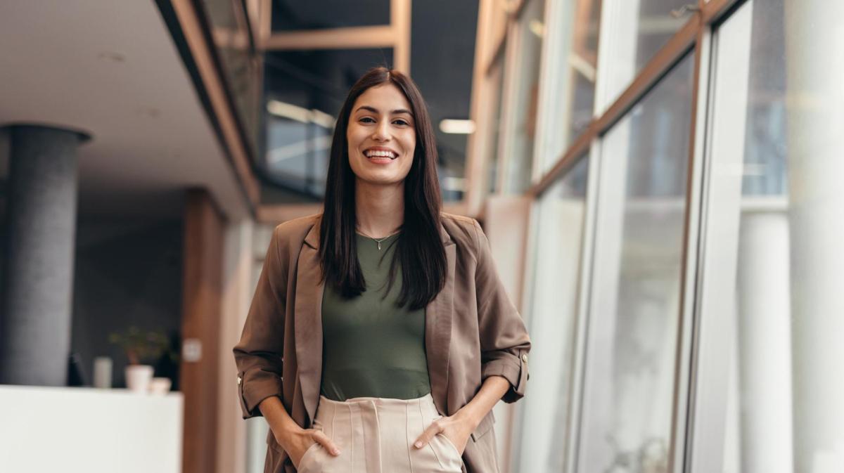 Frau mit braunen Haaren hat die Hände in den Hosentaschen.
